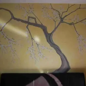 A chinoiserie painting of a tree on a bedroom wall, showcasing intricate design elements in a London setting.