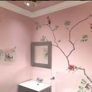 A bathroom featuring pink walls adorned with a chinoiserie tree mural, showcasing a stylish design in London.