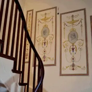 A staircase beside a wall adorned with pictures from a mural project, showcasing vibrant artwork and creative designs.