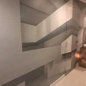 A hallway featuring a large mural of geometric shapes, showcasing a vibrant mural project on the wall