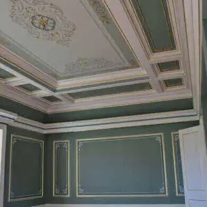A room adorned with green walls and gold accents, prominently displaying a creative mural project.