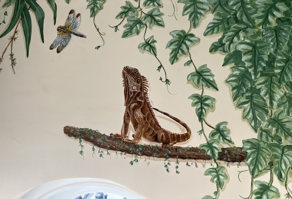 A detail of an iguana and dragon fly in a mural